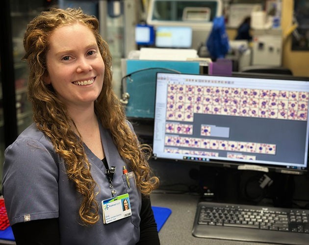 Photo of Gina LaMothe standing in front of a computer screen with blood samples