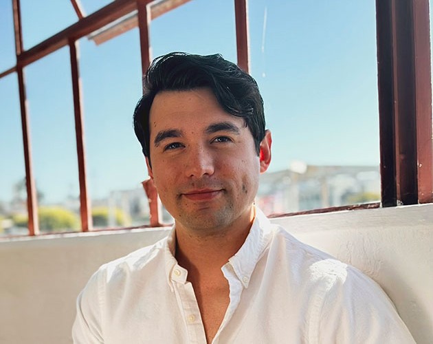 Headshot of Isaac Stuart sitting on a white couch