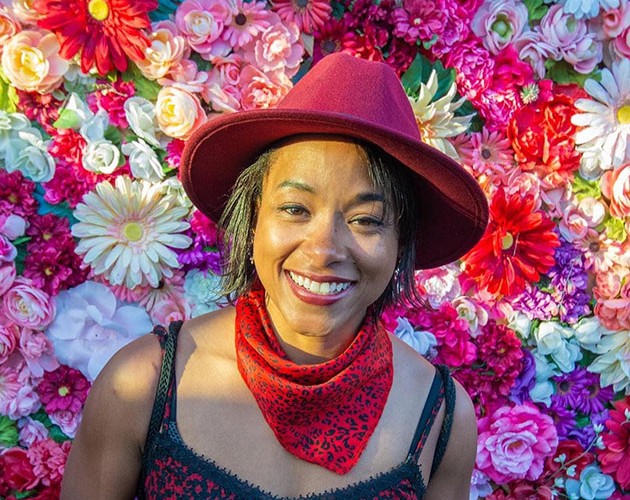 Photo of Sandra Titre in front of a wall of flowers