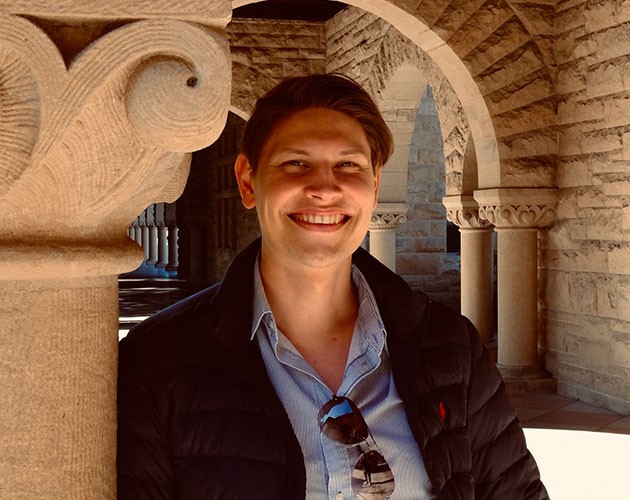 Photo of Tom Luis Hueter standing in front of an archway