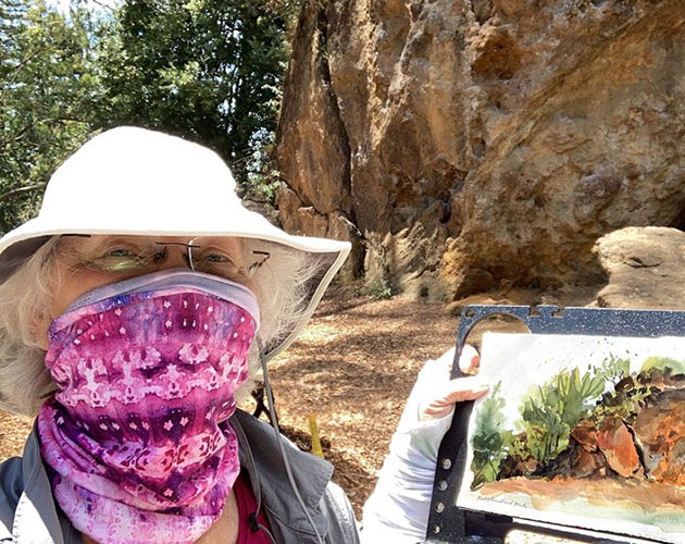 Jennifer Mahoney wearing a face mask while holding recent painting