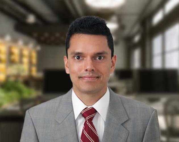 Headshot of Ameer Acharya wearing a gray suit and a red tie