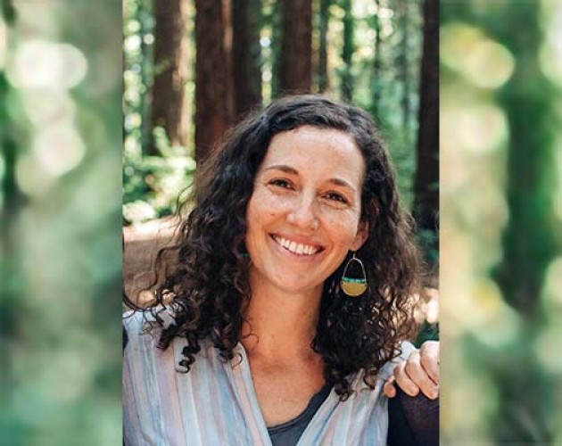 Photo of ESL Teacher Dana Neufeld in the forest wearing a rainbow shirt