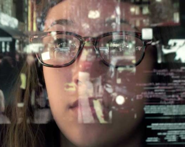 Data analyst gazing at glass wall covered in reflected data