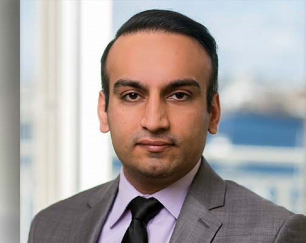 Headshot of Personal Financial Planning graduate Sandeep Gandhi wearing a gray suit, standing in front of a window. Photo.