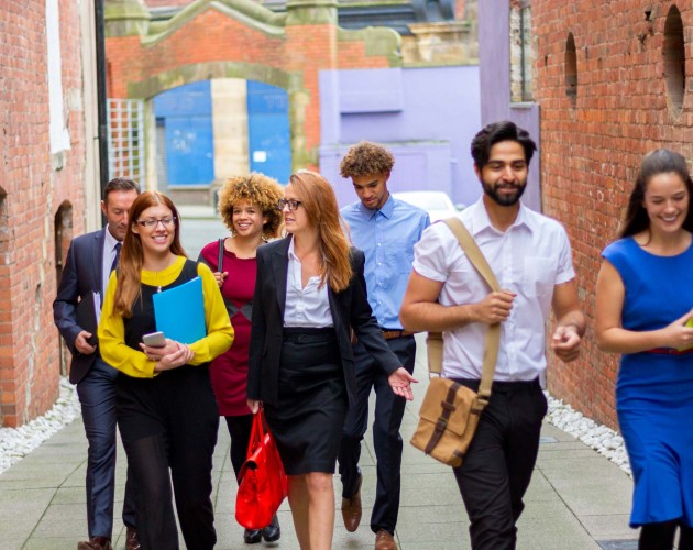 A group of seven young professionals and students walks down the street