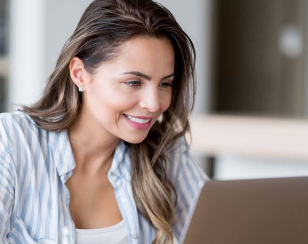 Woman in blue striped shirt viewing laptop