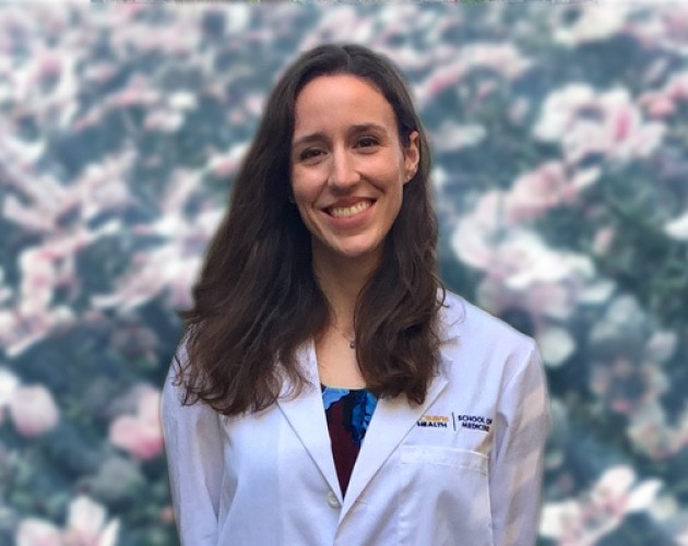 Photo of Laura Potter wearing white medical jacket in front of flower background