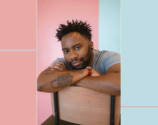 Photo of Reiss Reid sitting on a chair backward in front of a pink and blue background