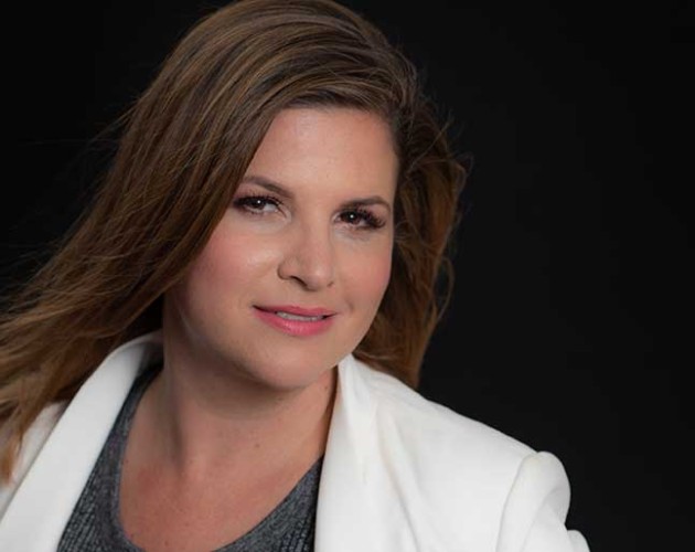 Instructor Renae Valdes wearing a white jacket in front of a black background