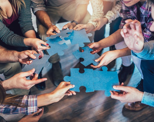 Photo of people holding blue pieces of a puzzle