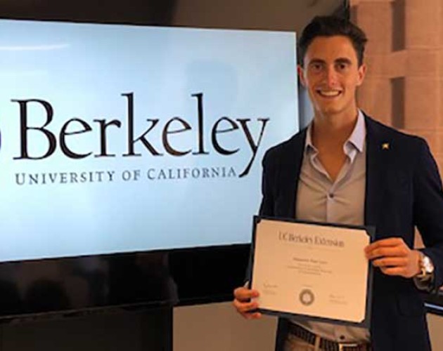 Photo of Alejandro Ruiz holding certificate of completion in front of a TV screen with Berkeley logo