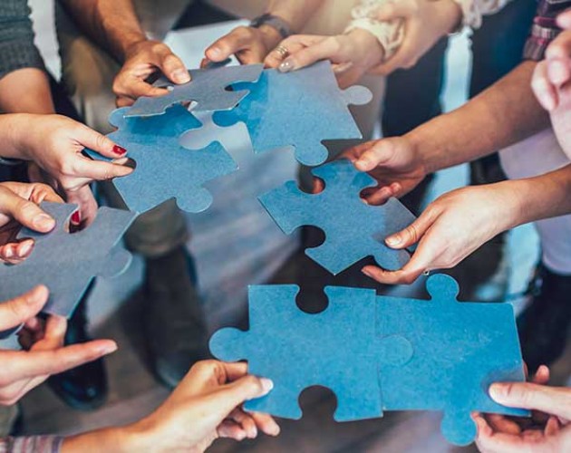 Group of diverse professionals holding jigsaw puzzle pieces