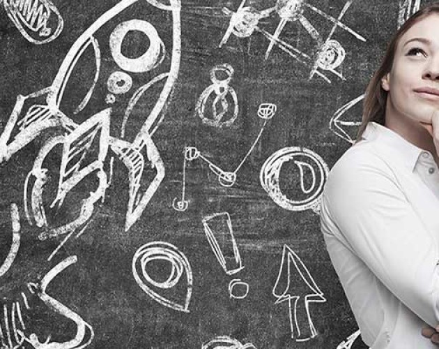 Business icons on blackboard with white young female professional standing in front