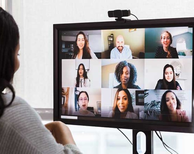 Photo of black young professional collaborating with team through online conferencing