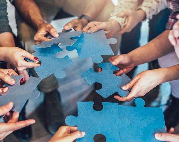 Photo of hands holding pieces of a jigsaw puzzle