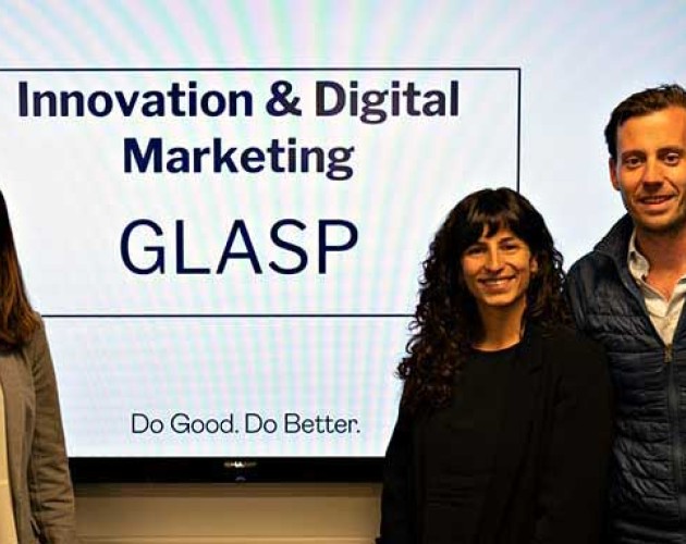 Custom programs students standing in front of digital display of their GLASP marketing presentation