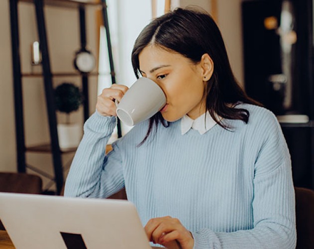 Stock photo of woman working from home and drinking coffee