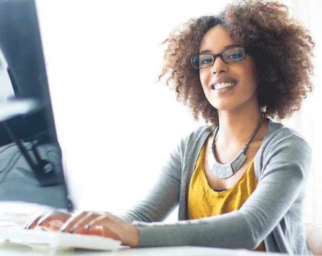 young professional typing on a computer keyboard looking at camera