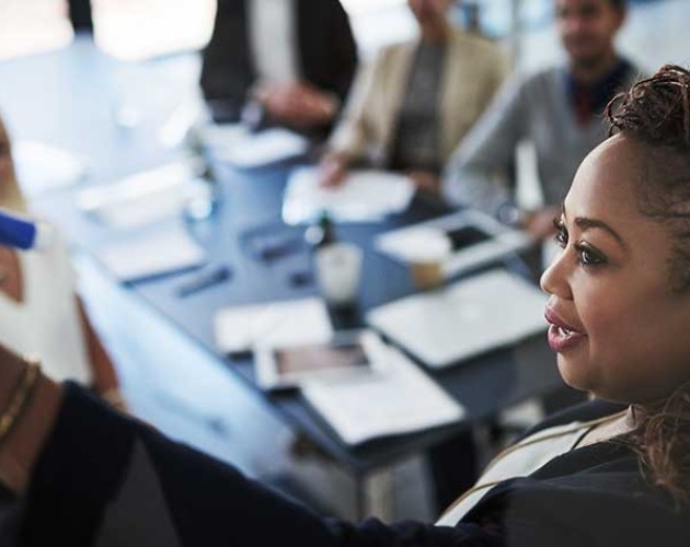 Black woman professional leading meeting while drawing on a white board