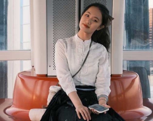 Lydia Bao sitting on an orange round couch in front of windows