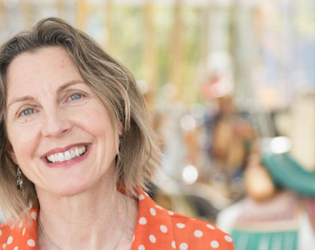 Writing certificate graduate Nancy Tompkins standing off-center in front of a carousel