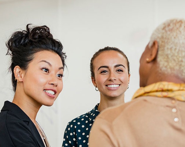 Colleagues in an office setting, standing and discussing ideas with interest