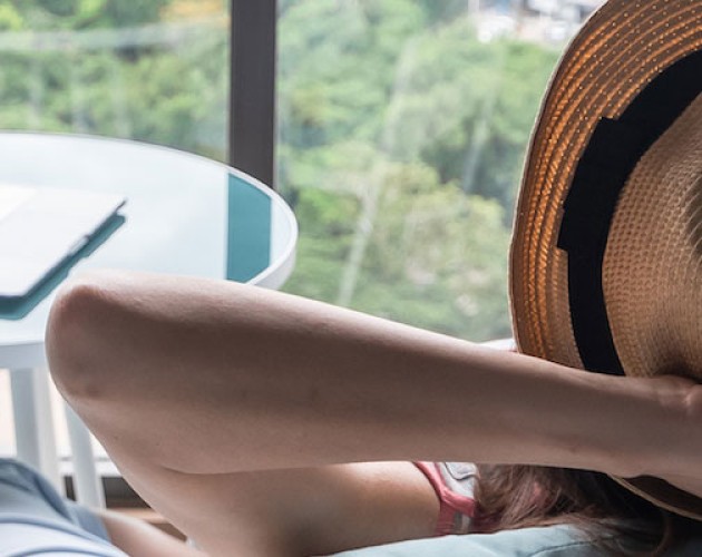 Stock photo of a woman with arms crossed behind her head in relaxation after working on her novel on a laptop.