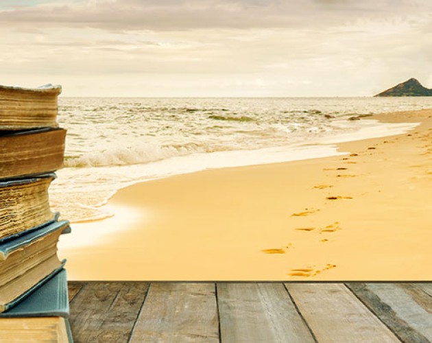 stock photo of a stack of books on a woden table by the beach