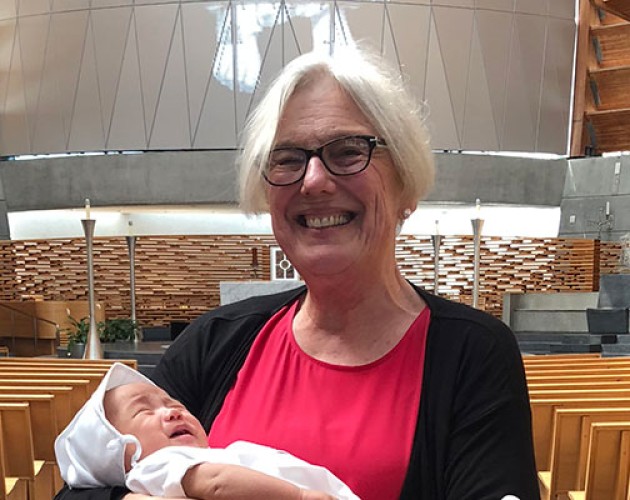 Photograph of Alcohol and Drug Abuse Studies graduate Therese Becker holding her grandson at his baptism