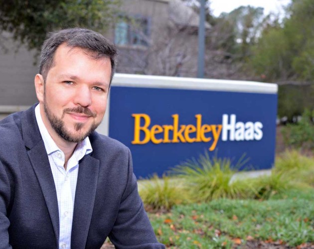 Thiago Santos Medeiros poses and smiles next to the Haas school of business sign on campus.