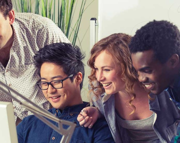 Photo of four diverse young professionals looking at a computer screen