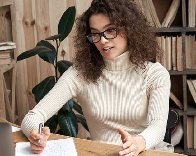 Young Latin female professional taking an online class and looking at laptop monitor