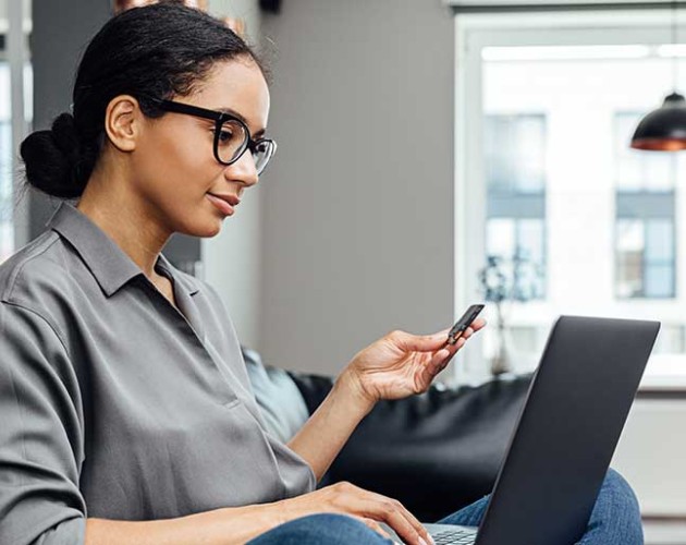 Photo of woman sitting on couch while working on a laptop