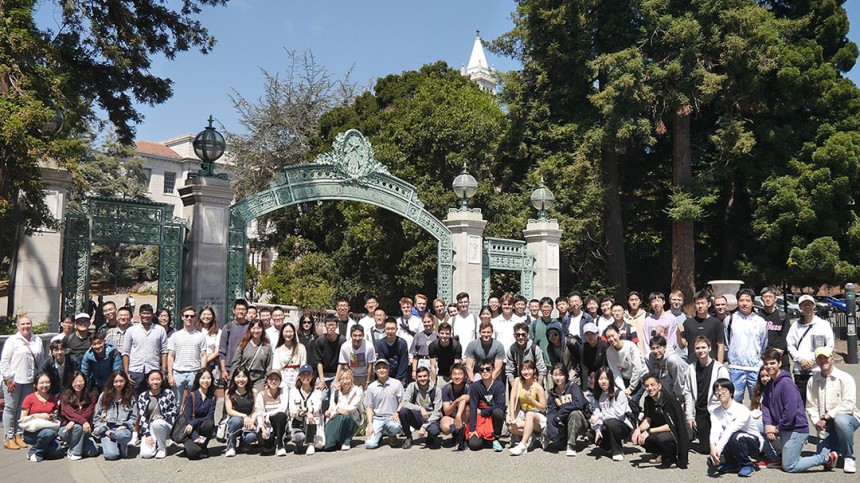 Group of students take a photo in front of Sather Gate