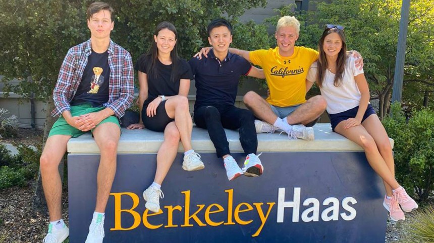 Aliona Margulis and friends sitting on a Berkeley Haas sign