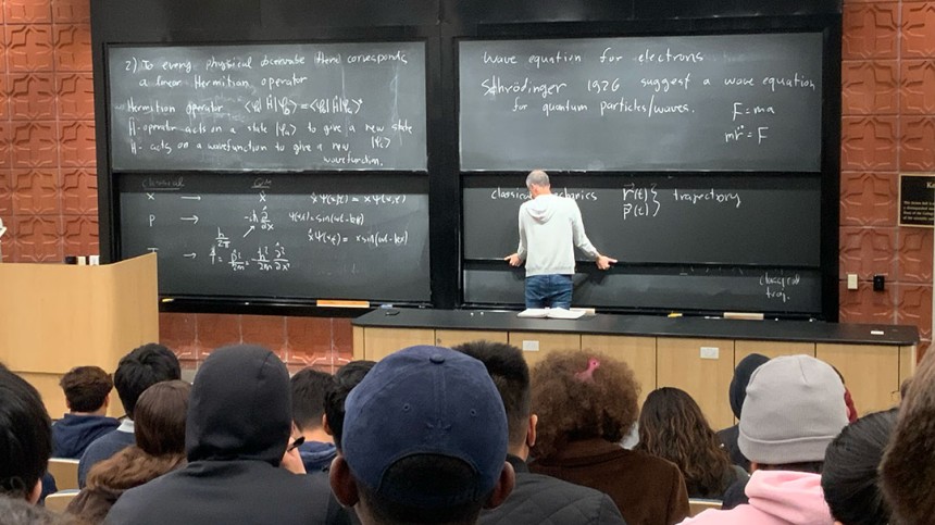 Photo of a teacher in front of a black board